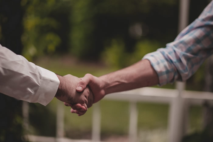 Manos apoyadas en una mesa de madera con un sobre enviando una carta